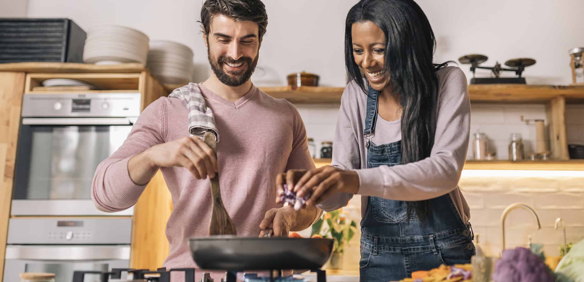 Cute couple smiling and preparing lunch together in the kitchen at home.