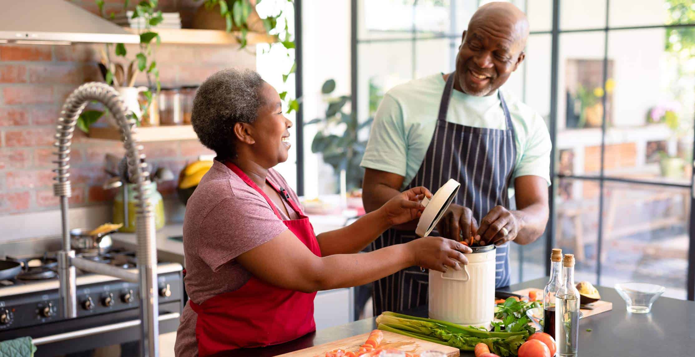 Happy african american senior couple cooking together in kitchen. retirement lifestyle, leisure and spending time at home.